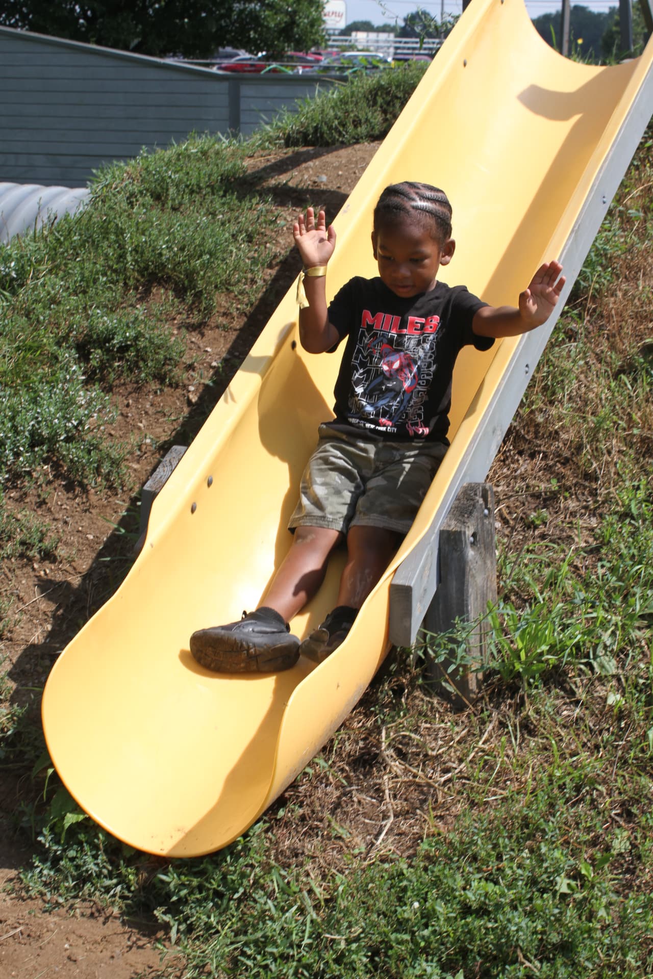 A preschooler sliding down the yellow playground slide