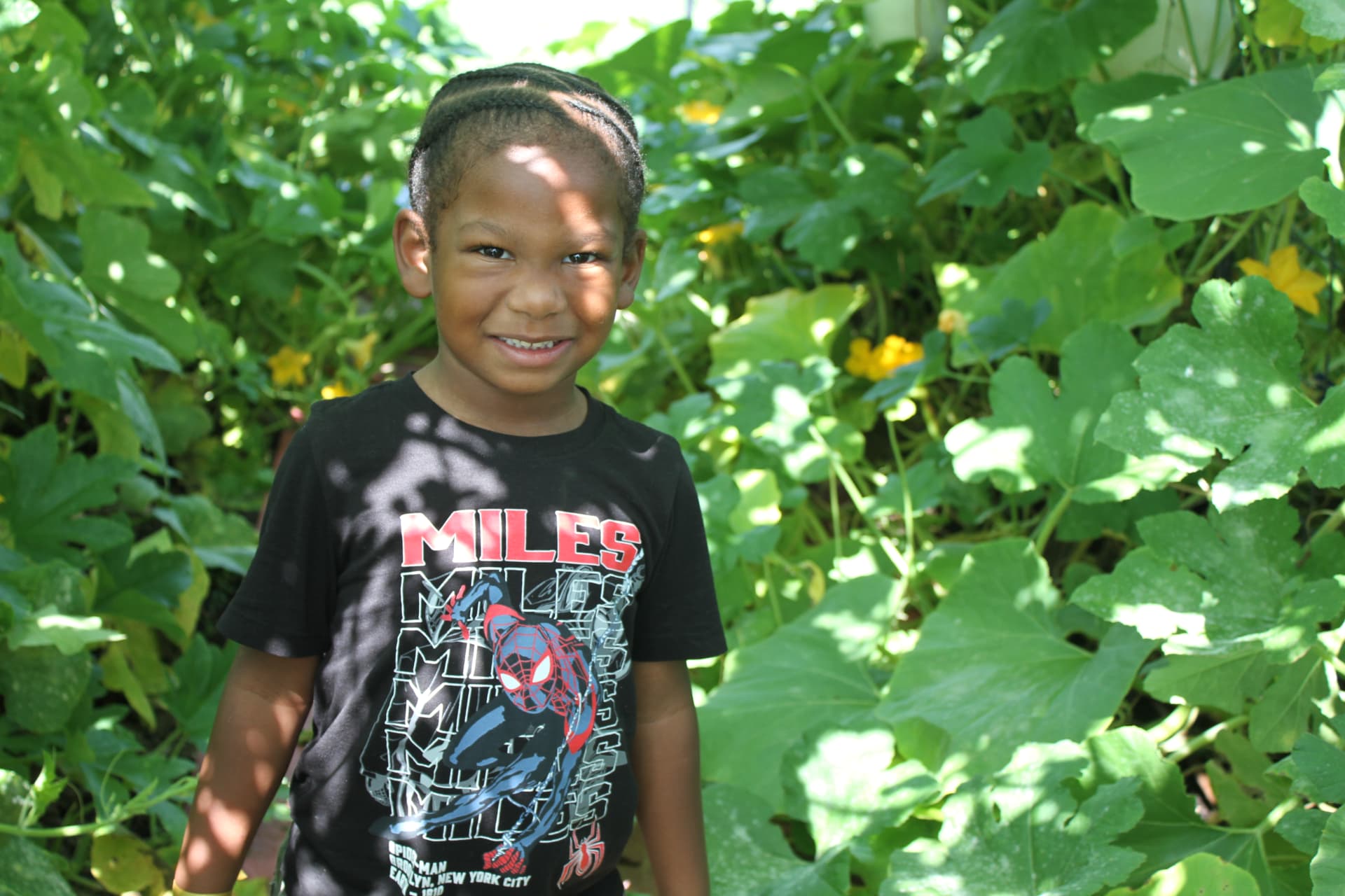 A smiling preschooler among the garden vines